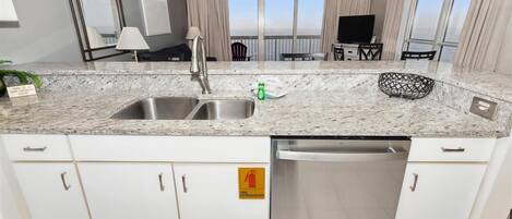 A modern kitchen with a granite countertop, stainless steel appliances, and a view of the ocean.