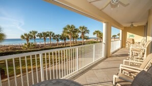 A balcony with a view of the beach, palm trees, and ocean.
