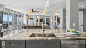 A modern kitchen with a large island, stainless steel appliances, and pendant lighting.