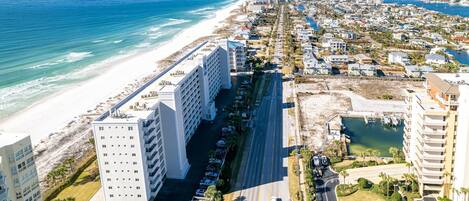 Un paisaje urbano costero con un hotel frente a la playa, un puerto deportivo y edificios residenciales densos.