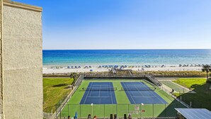 A tennis court with a view of the beach and ocean.