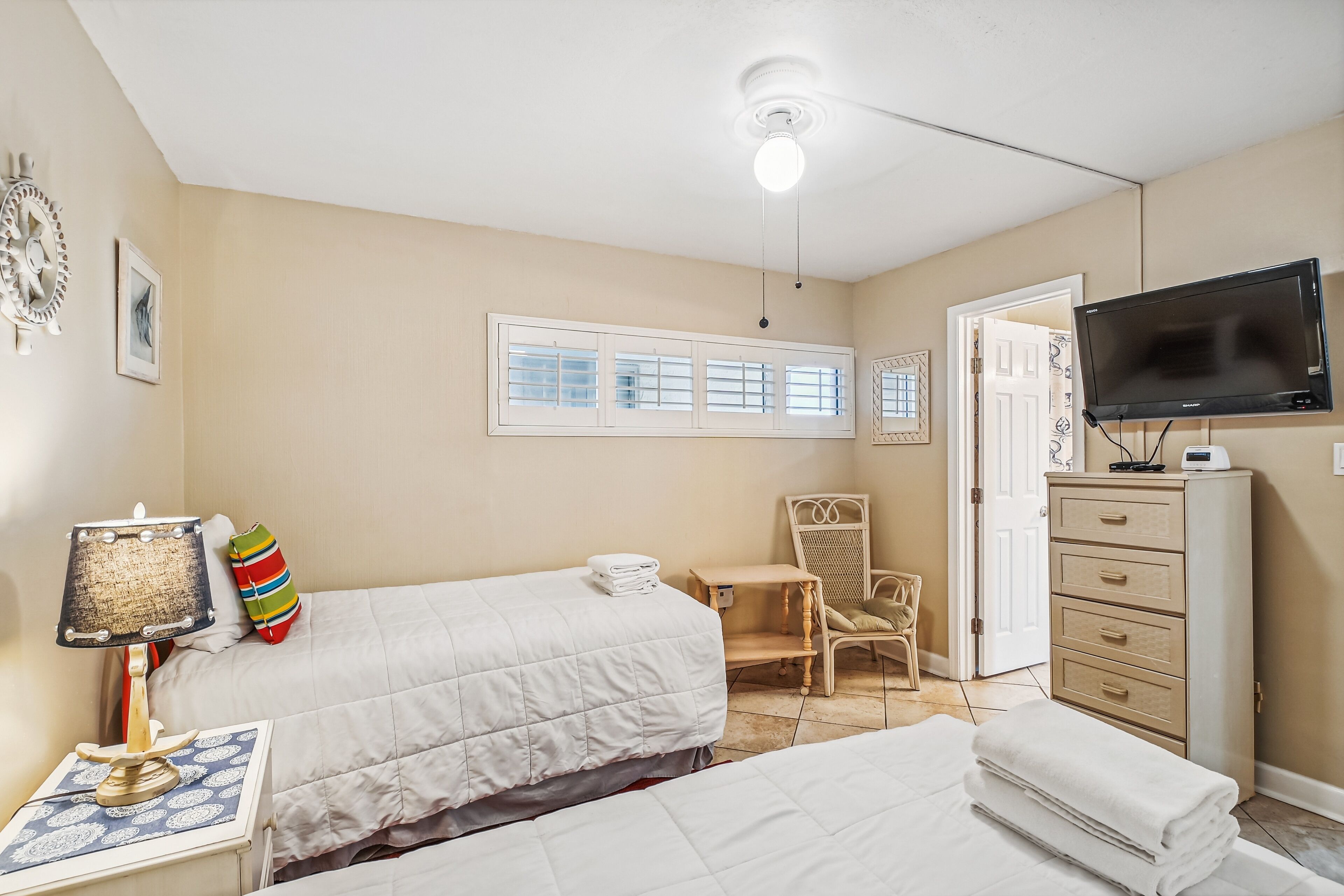 A hotel room with two beds, a desk, a chair, a television, and a wardrobe.