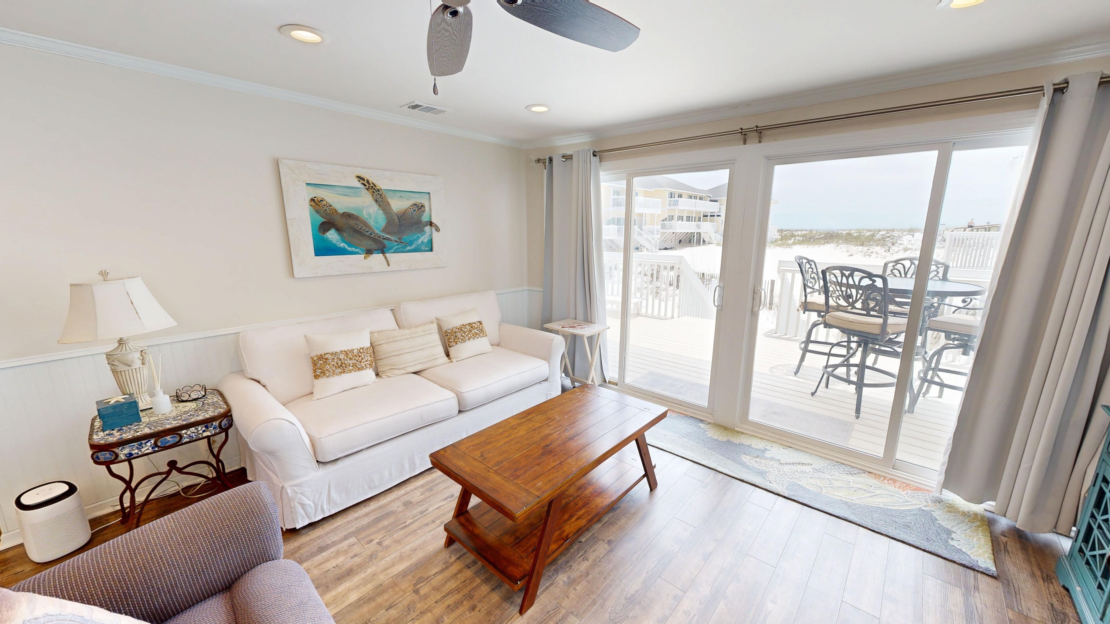A living room with a white sofa, a wooden coffee table, and a painting of a sea turtle.