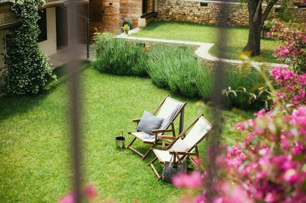 A garden with two wooden chairs, a stone wall, and a pathway. - Mas Ferran Adults Only (Pals)