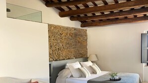 Une chambre avec un lit, un canapé, un mur en pierre et un plafond en bois.