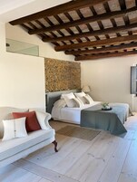 Un dormitorio con una cama, un sofá, una pared de piedra y techo de madera.