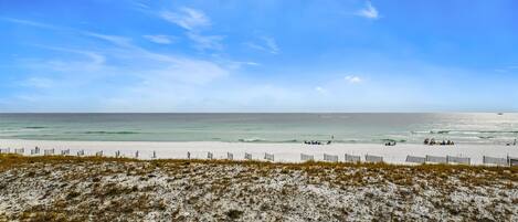 A beach with a sandy foreground and a wooden fence.
