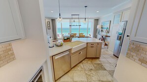 Una cocina moderna con una isla central, lavavajillas integrado y vistas al mar.