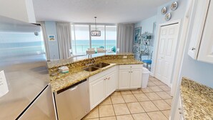 A kitchen with granite countertops, stainless steel appliances, and a view of the ocean. - Oceania 607 3 Bedroom Condo by RedAwning (Destin)