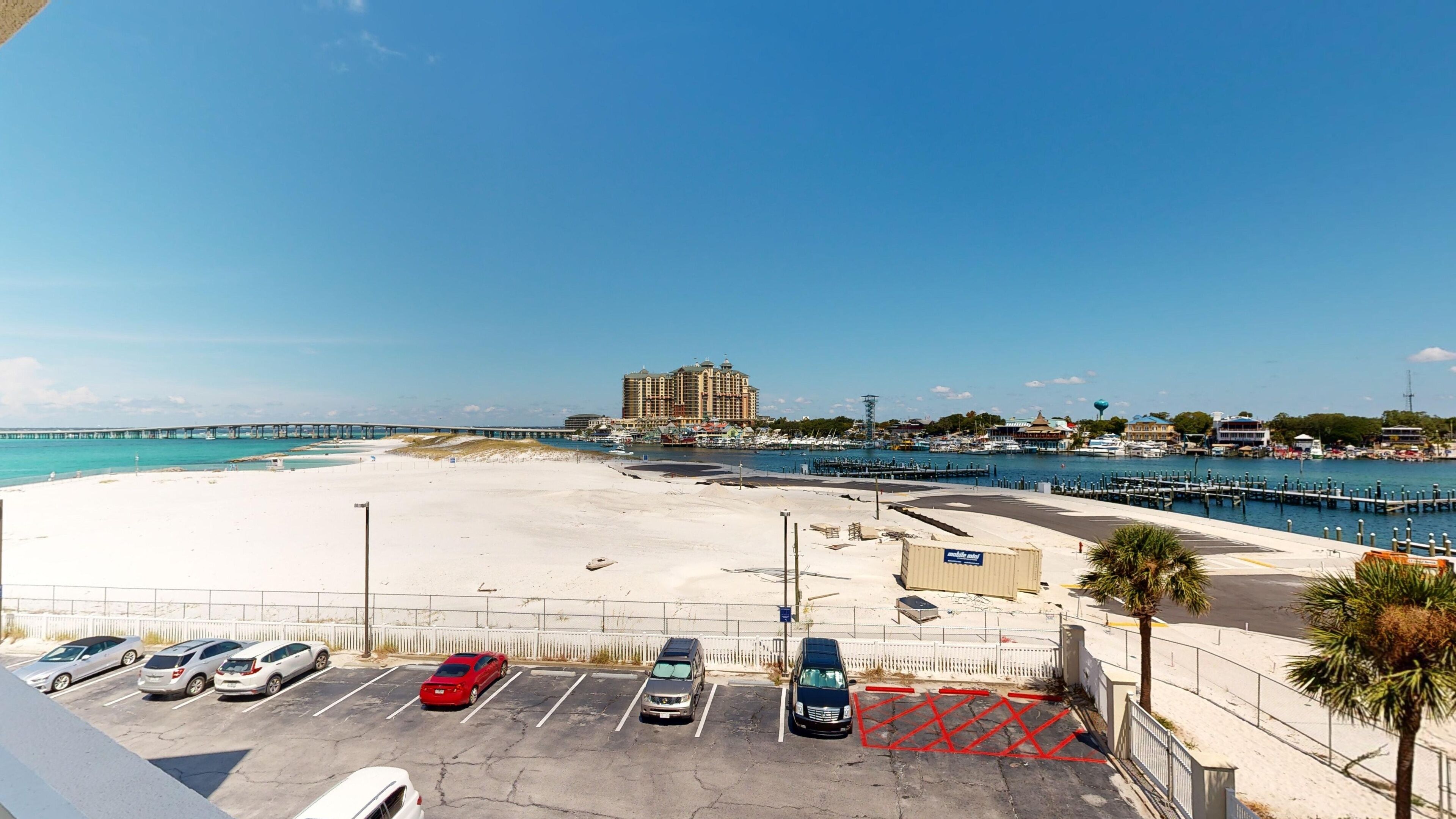 Un hotel frente a la playa con estacionamiento, un muelle y un puerto deportivo.