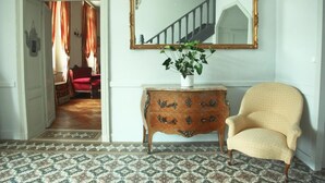 A room with a patterned floor, a wooden dresser with drawers, a chair, and a mirror on the wall. - Chambres d'hotes du Parc (Podensac)