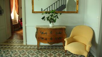 Una habitación con un aparador de madera, un sillón amarillo, un espejo grande y una planta en maceta.