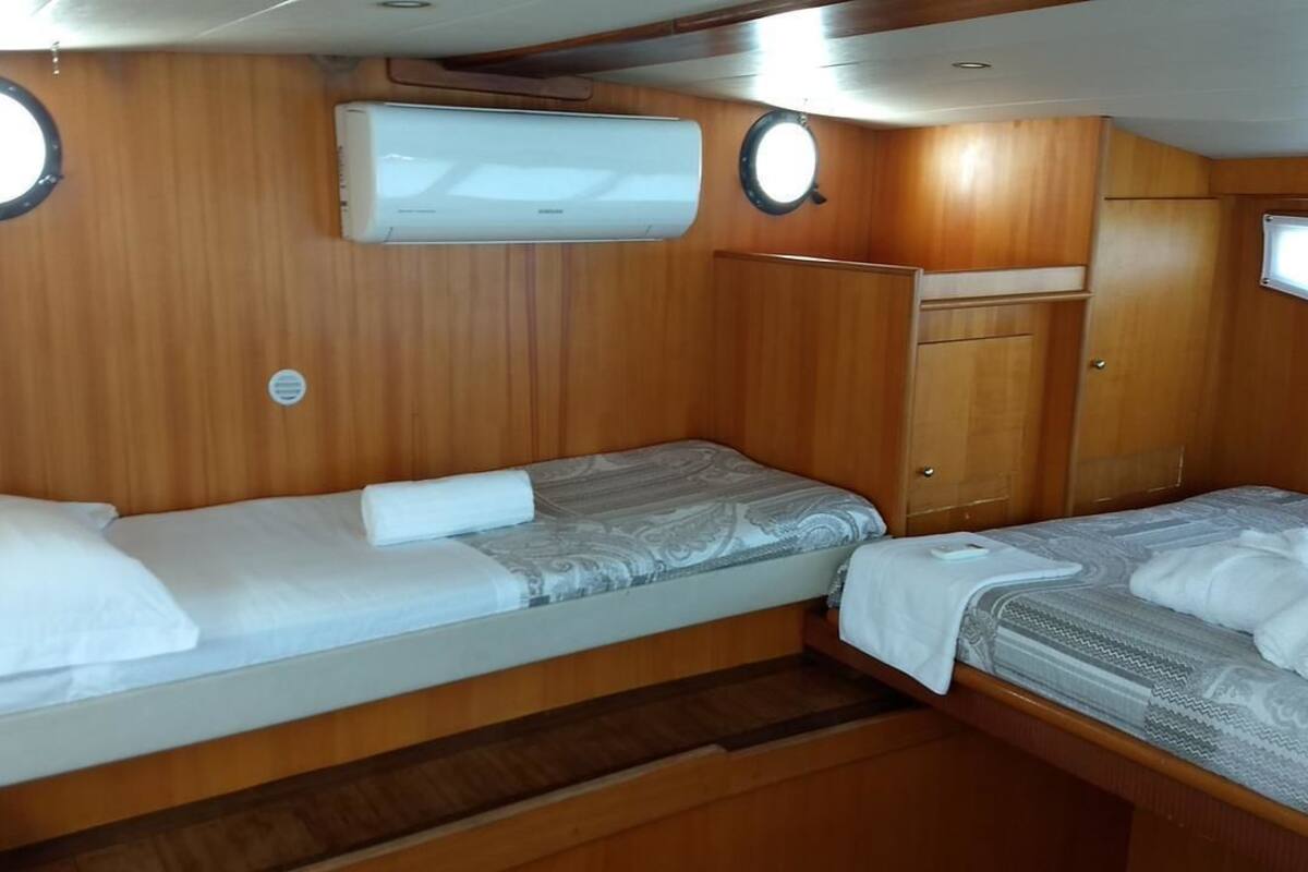 A compact cabin with two beds, wooden paneling, and a small wardrobe.