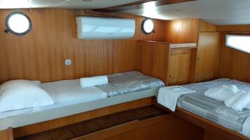 A compact cabin with two beds, wooden paneling, and a small wardrobe.