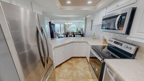 A modern kitchen with stainless steel appliances, white cabinetry, and a large island.