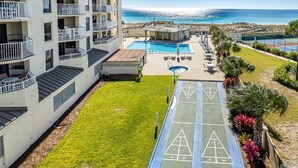 Un espace piscine comprenant un terrain de jeu de palet, un court de tennis et une vue sur l’océan.