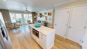 Una cucina moderna con pavimento in legno, un'isola centrale e una zona pranzo con sedie e tavolo.