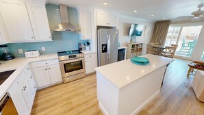 Una cucina moderna con mobili bianchi, elettrodomestici in acciaio inossidabile e una grande isola.