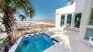 A modern outdoor pool area with a clear view of the beach and ocean.