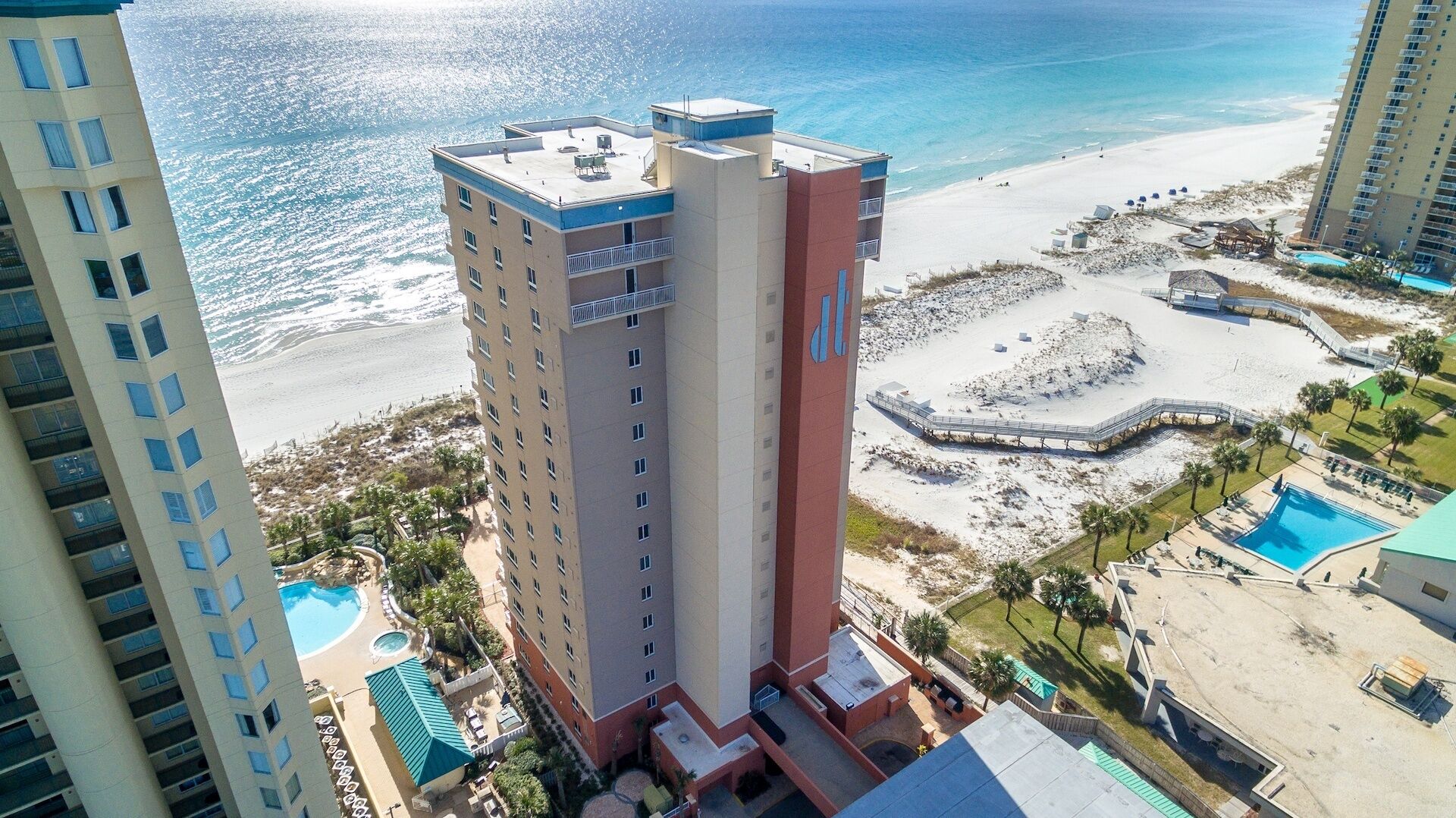 A high-rise hotel with a rooftop pool, beach access, and a beach area with a circular walkway.