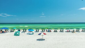 A beach with rows of umbrellas and beach chairs. - Destin On The Gulf 505 2 Bedroom Condo by RedAwning (Destin)