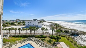 A beachfront hotel with a pool, palm trees, and a view of the beach and ocean. - Destin On The Gulf 505 2 Bedroom Condo by RedAwning (Destin)