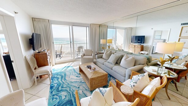 A spacious living room with a large sofa, a coffee table, and a view of the ocean through large windows. - Destin On The Gulf 505 2 Bedroom Condo by RedAwning (Destin)