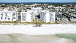 Un hotel frente a la playa con varios edificios altos, un patio central y vistas al océano.