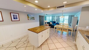 Una cocina moderna con armarios blancos, encimera de granito y un comedor con mesa y sillas.