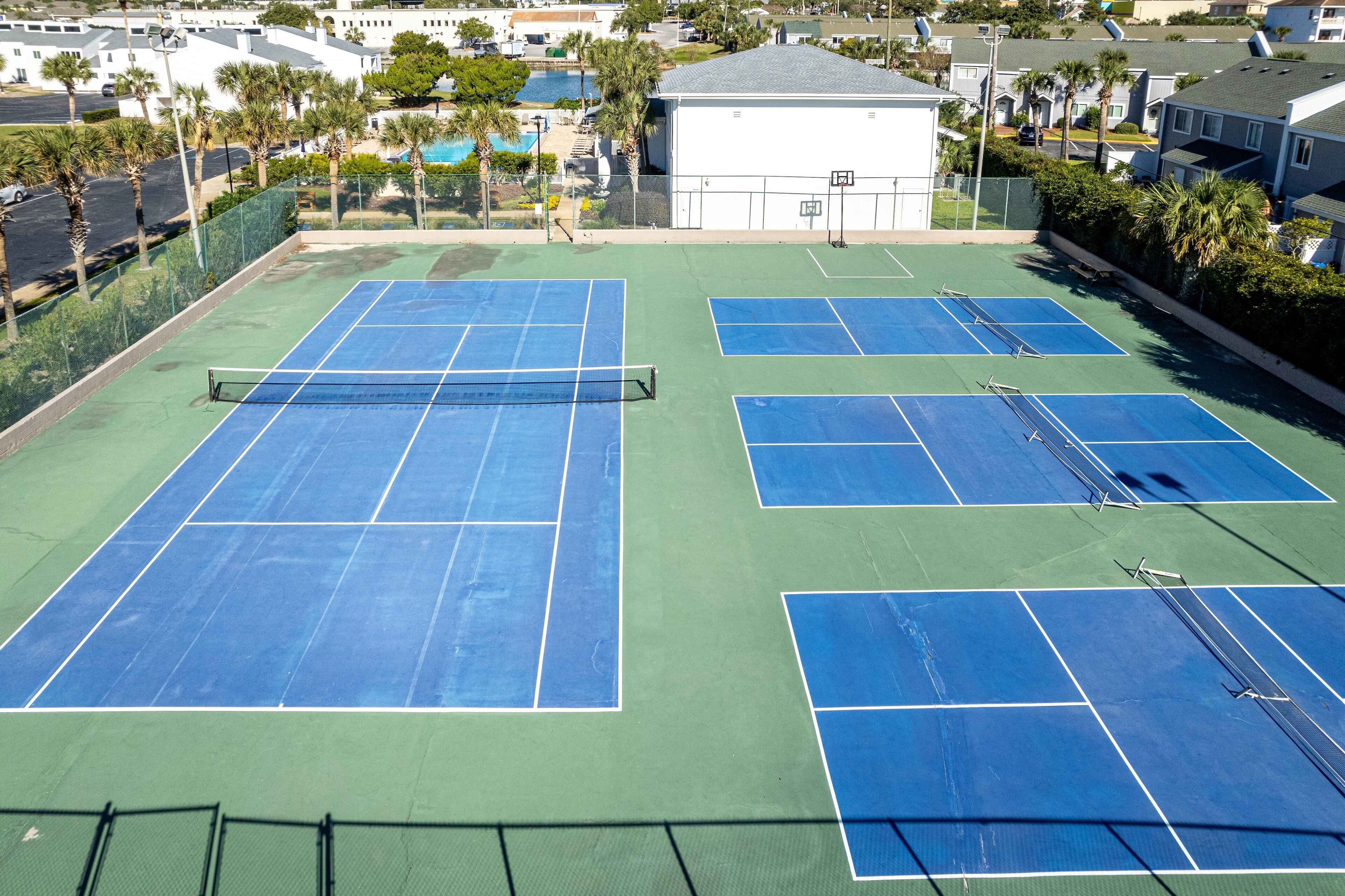 Canchas de tenis múltiples, rodeadas por una valla, y adyacentes a un edificio.