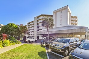 A multi-story building with balconies, a sign reading "HOLIDAY SURF 510", and a parking lot with several cars. - Holiday Surf & Racquet 402 2 Bedroom Condo by RedAwning (Destin)