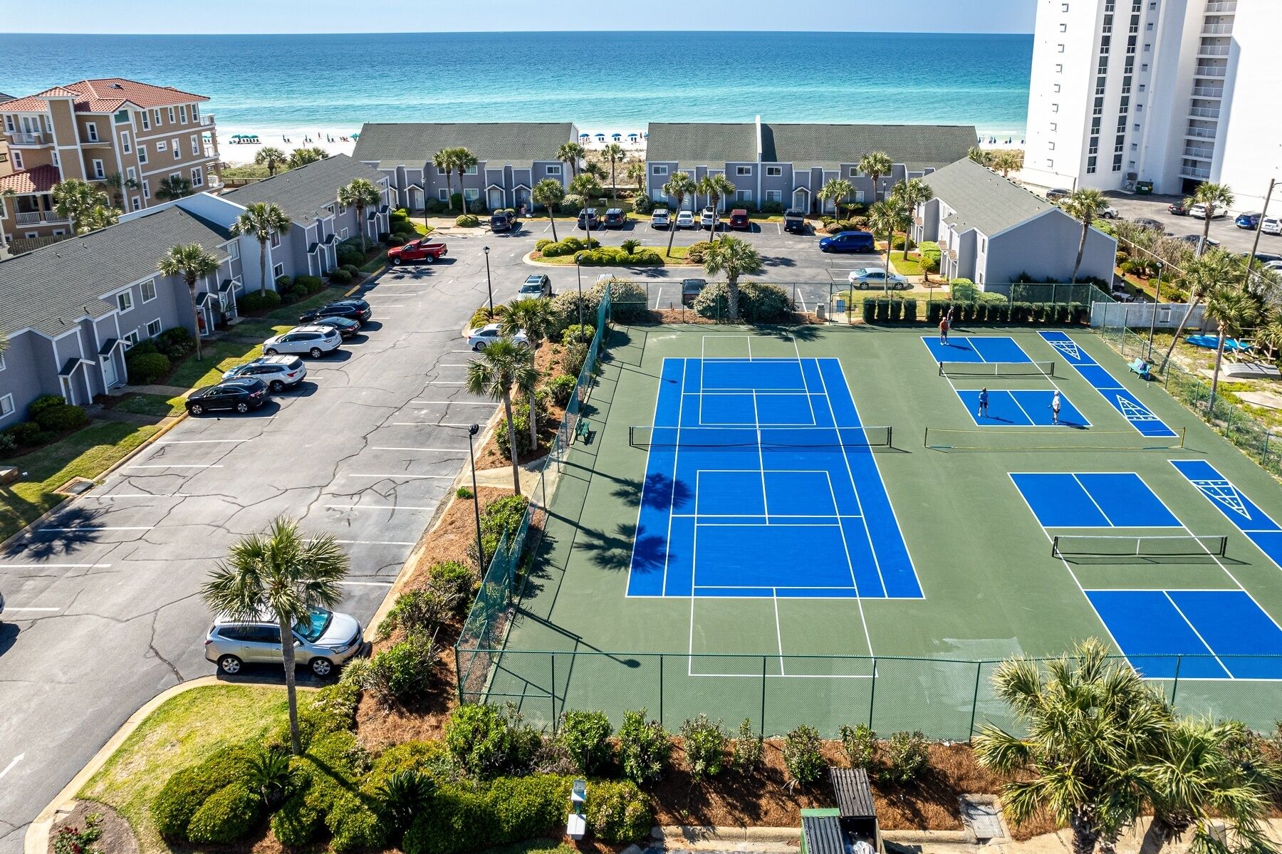 Edifici de diverses plantes amb aparcament i pistes de tennis.