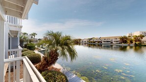 Ett hotell vid vattnet med en pool, palmer och utsikt över stadens silhuett.