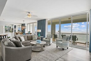 A spacious living area with a large sofa, armchairs, and a coffee table. There is a balcony with a view of the ocean. - Oceania 503 3 Bedroom Condo by RedAwning (Destin)