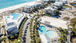 A coastal resort with multiple swimming pools, beachfront villas, and a sandy beach.