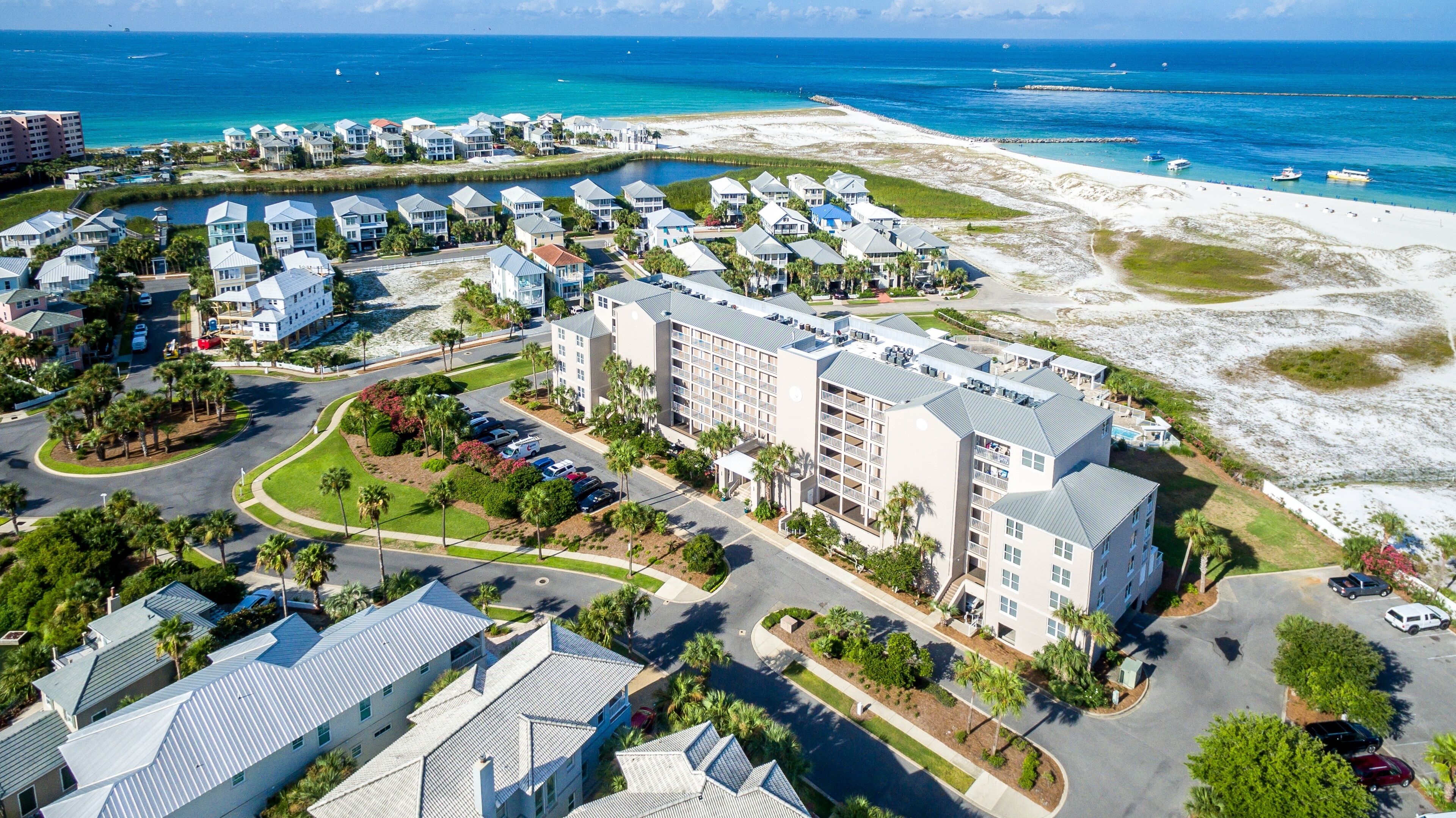 A resort with beachfront villas, a central building with multiple floors, and a parking area.