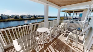A covered outdoor deck with white railings, a round table, and matching chairs.