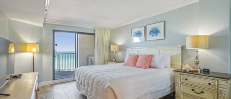 A hotel room with a bed, bedside lamps, a nightstand, a dresser, and a view of the outside.