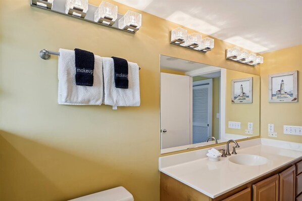 A bathroom with a large mirror, two towels hanging on a towel rack, a sink with a faucet, and a vanity cabinet.