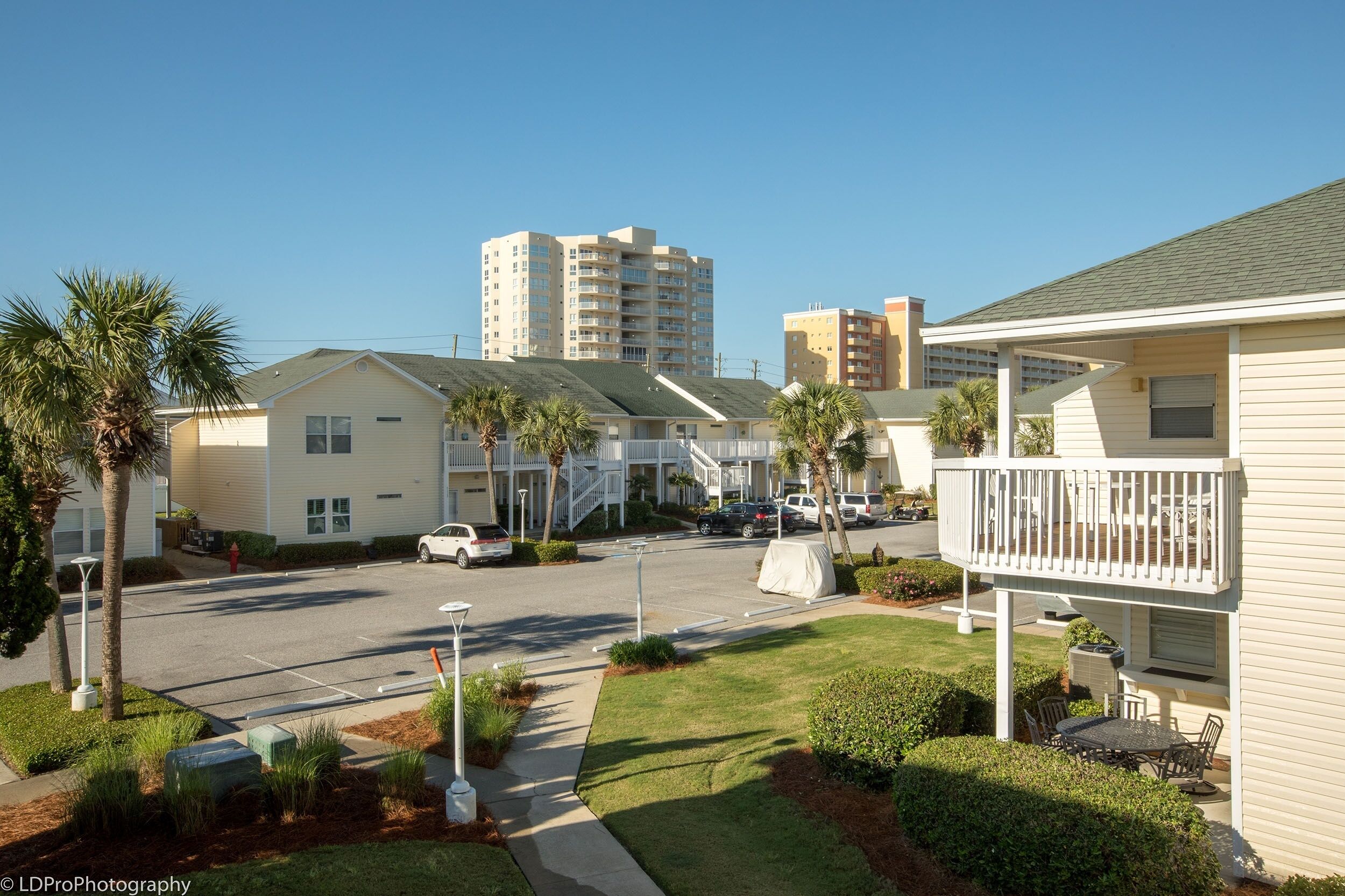 A residential area with multiple two-story houses, a parking lot, and a clear sky.