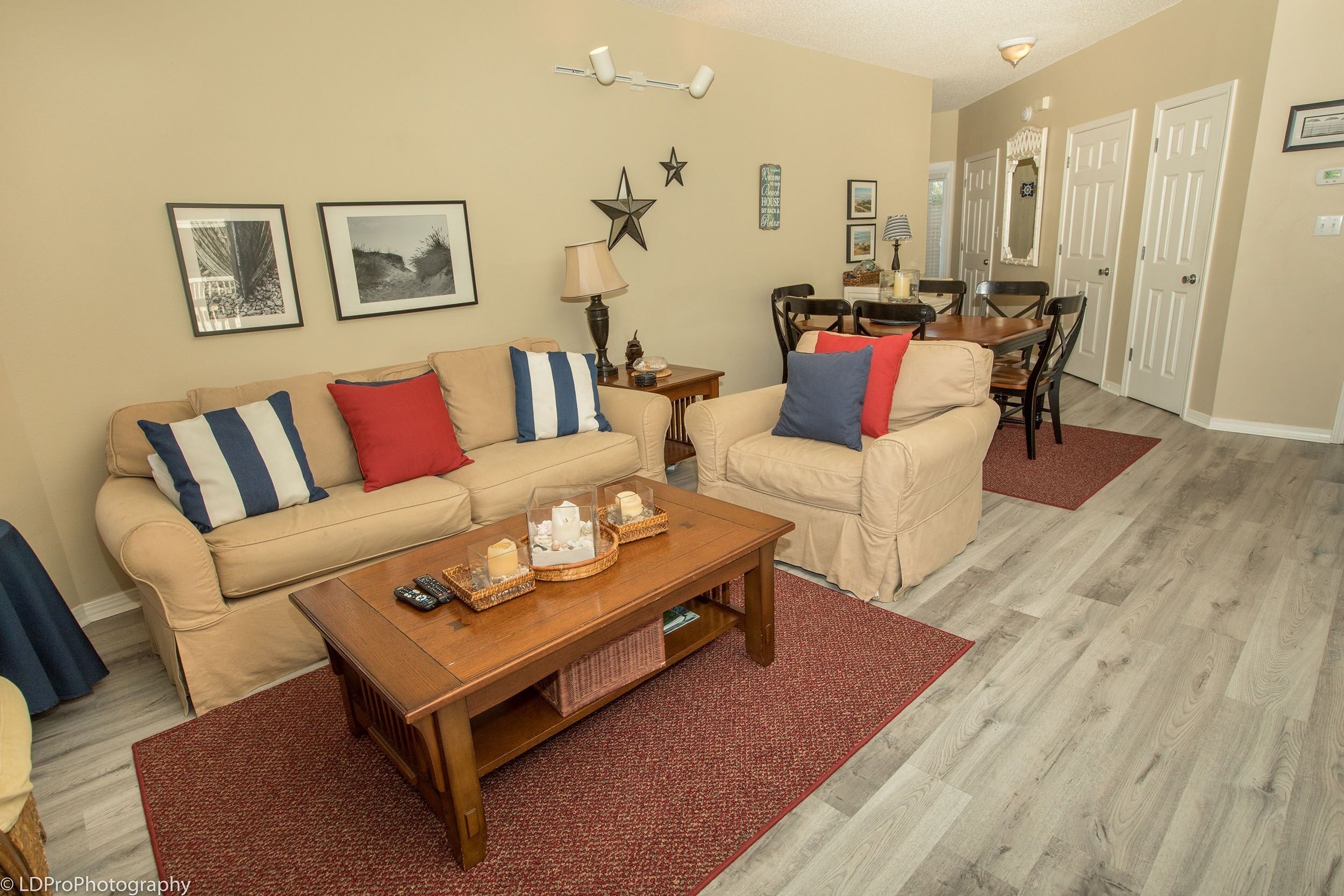 Un salón con un sofá color beige, una mesa de centro de madera y una zona de comedor con una mesa y sillas.