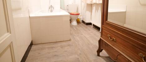 Un baño con bañera, inodoro y tocador de madera.