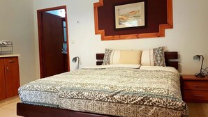 A bedroom with a bed, a nightstand, a dresser, and a door. - Idan Lodge In The Arava (HaArava HaTikhona)