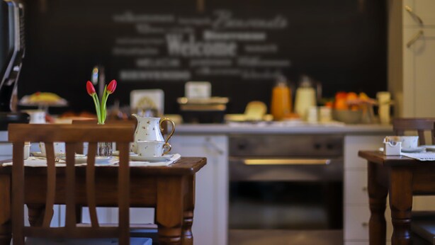 Ein Restaurantinneres mit einer Kreidetafel, Holztischen und einer Vase mit Tulpen.