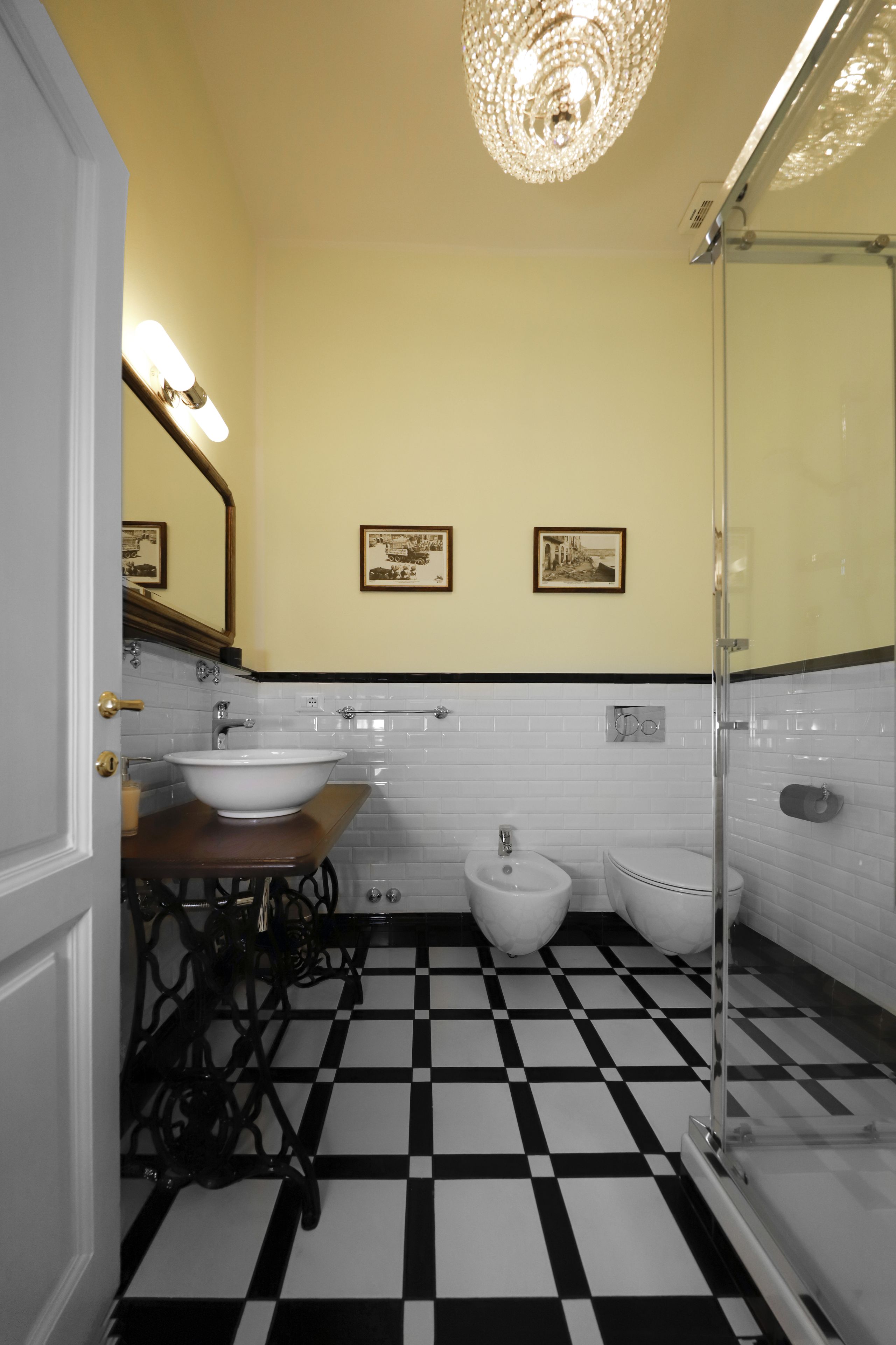 A bathroom with a checkered floor, a sink, a bidet, and a glass shower enclosure.