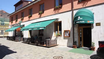 Un hotel con asientos exteriores y un toldo verde.
