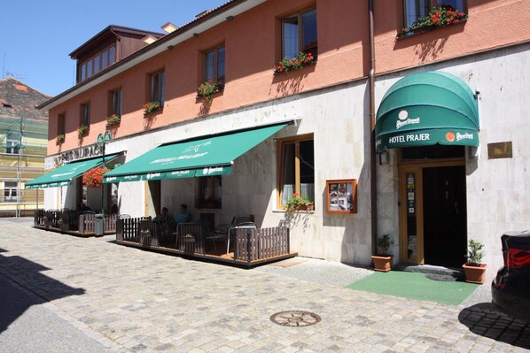 A hotel with outdoor seating and a green awning.