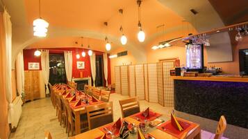 A restaurant with multiple dining tables, chairs, and a bar area.
