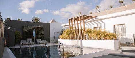Una piscina al aire libre, sillones reclinables de piscina