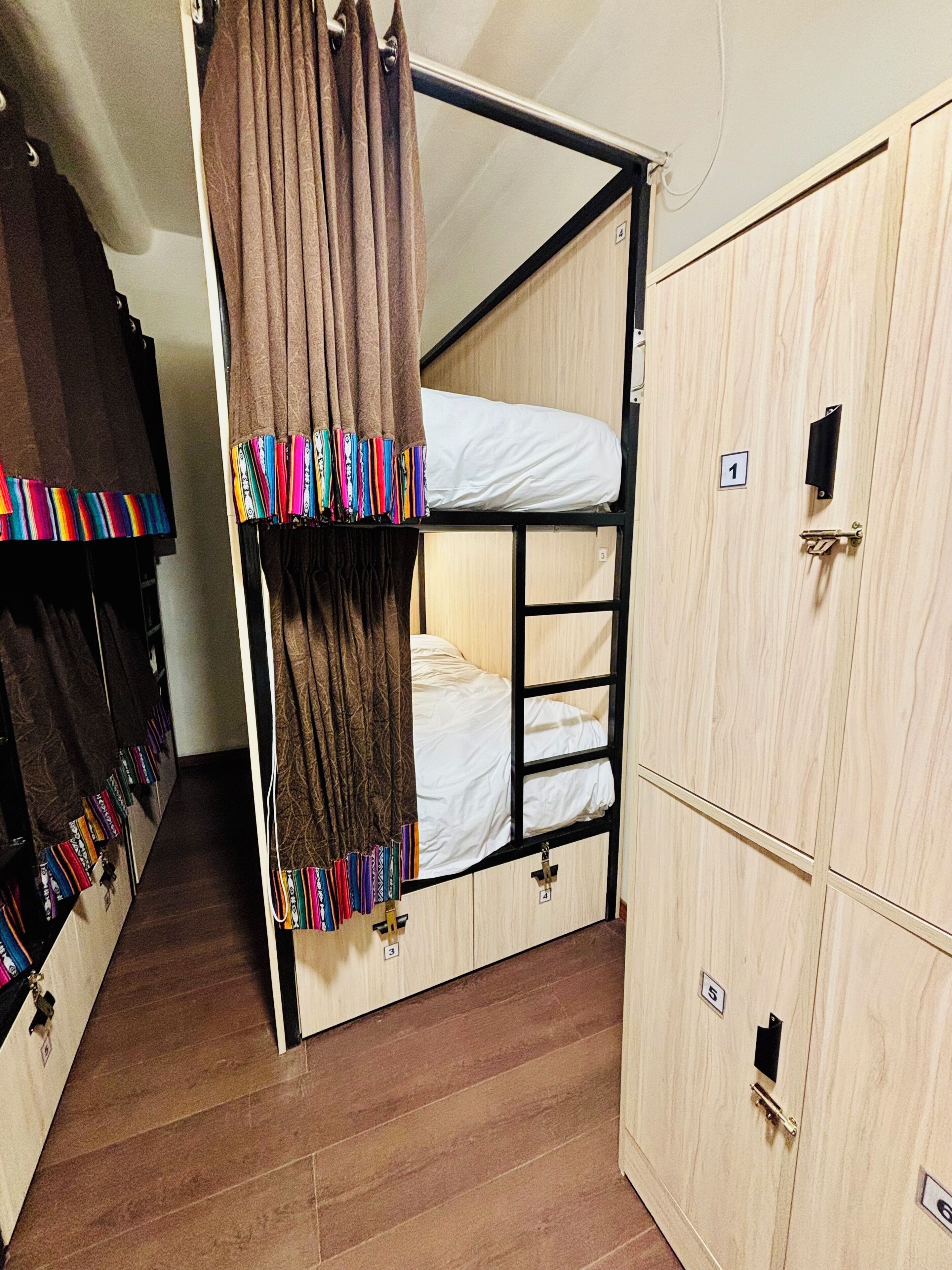 A bunk bed room with a wooden wardrobe and a door with a number.